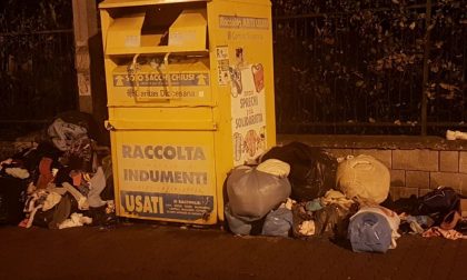 Cumuli di sacchetti con indumenti lasciati per terra vicino al cassonetto Caritas di Strada San Martino