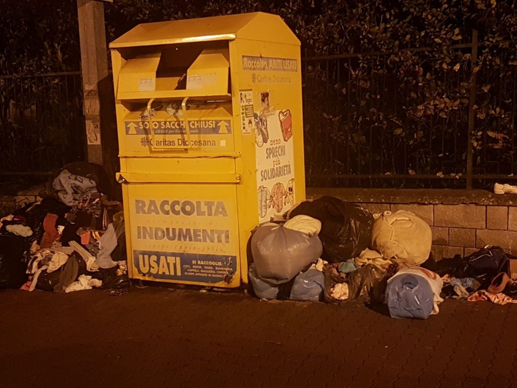 Cumuli di sacchetti con indumenti lasciati per terra vicino al cassonetto Caritas di Strada San Martino