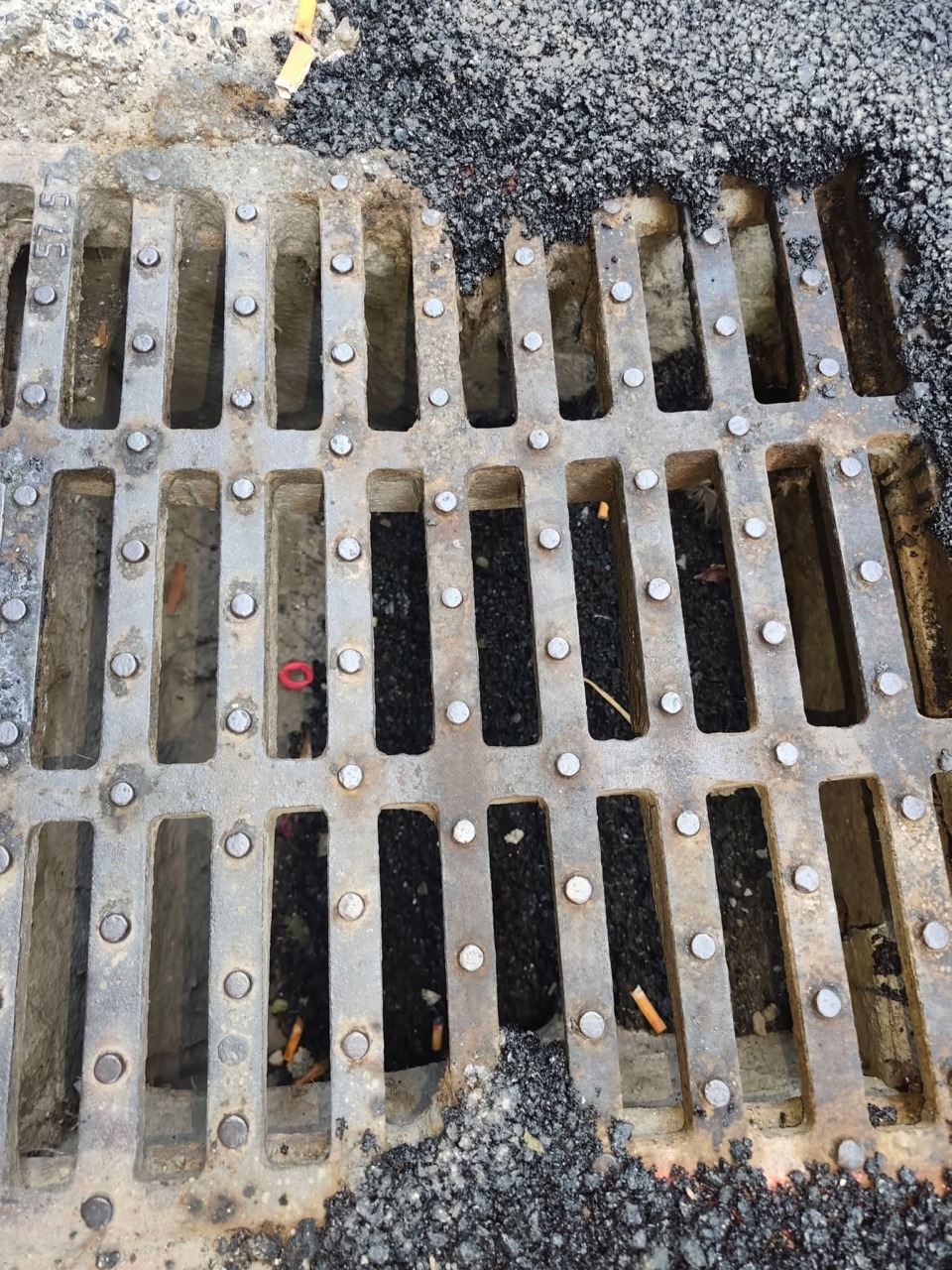 Catrame nelle griglie di scolo dopo la riasfaltatura per la fibra ottica